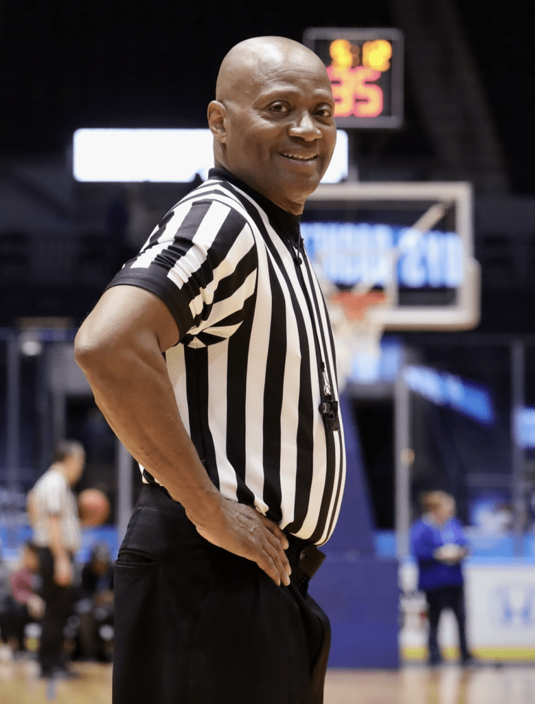 A referee is standing in front of the crowd.